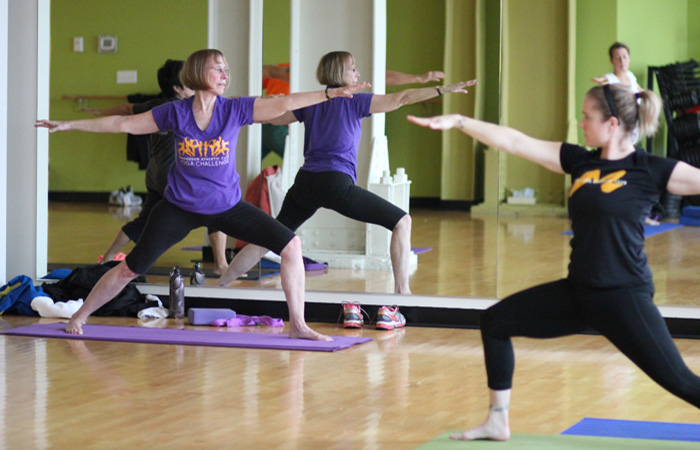 Trainer teaching group yoga class and doing a warrior pose