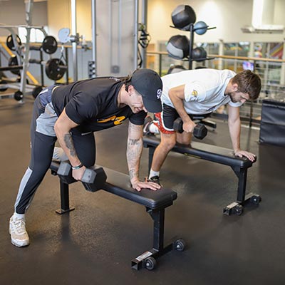 Two men perform a dumbbell exercise during Strength Training class at Magnuson Athletic Club in Seattle