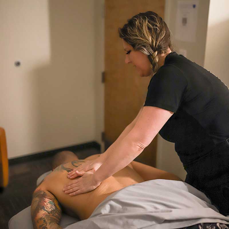 A masseuse massages a man's back in the Massage Lounge at Magnuson Athletic Club